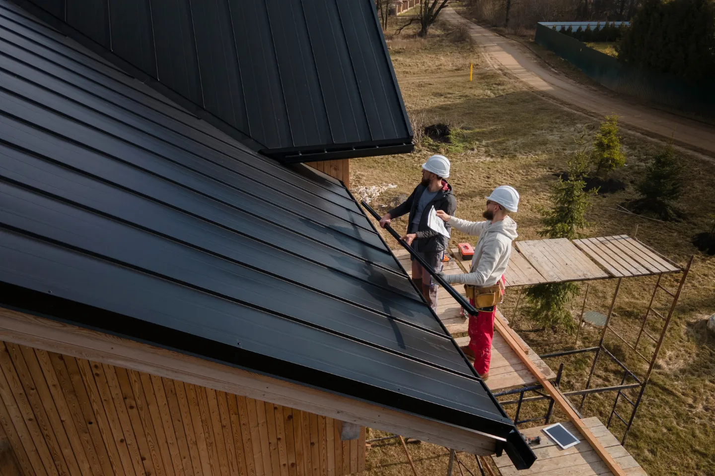 Professional roofers installing black panel roofing system
